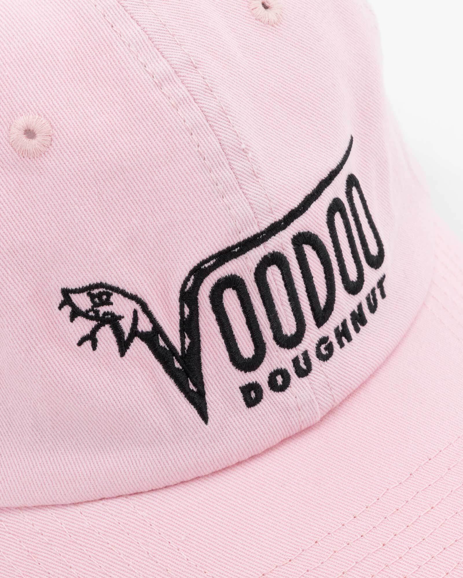 Pink cap with black 'Voodoo Doughnut' logo on a light pink background